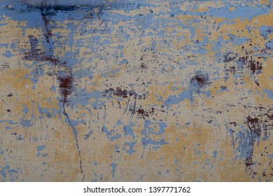 Peeling Paint Revealing Layers Of Blue, Yellow And Brown. Smudges Of Purple Add Texture. 