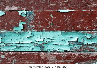 Peeling paint texture background. Peeling and cracked paint on a weathered wooden surface, featuring layers of dark red and turquoise or light blue-green paint