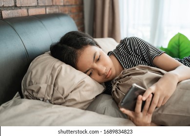 peer pressure. young teenage asian girl feel depress while using her mobile phone at home - Powered by Shutterstock