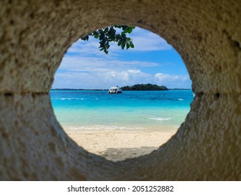 Peering Through A Stone Port Hole At A Boat Off The Coast Of Bora Bora