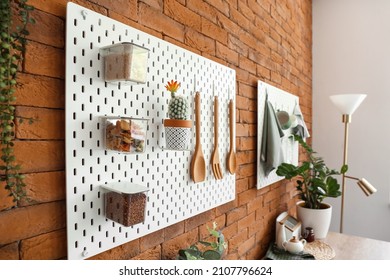 Peg Board With Kitchenware, Cactus And Food Hanging On Brick Wall