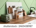 Pegboard with cookware and spices near green wall in kitchen