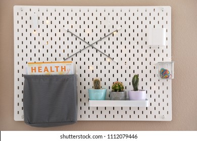 Pegboard With Different Cacti And Magazine On Wall