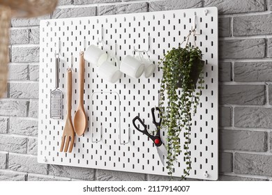 Pegboard With Kitchen Utensils On Grey Brick Wall