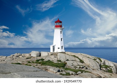Peggys Cove Lighthouse overlooking the water with white clouds
