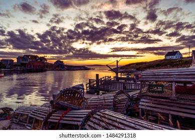 Peggy's Cove. Scenic view of a quiet fishing village on the Atlantic coastline of Nova Scotia, Canada. Close up of traditional wooden lobster pots against beautiful sunset sky