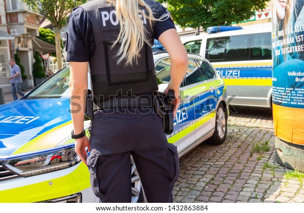 PEINE / GERMANY -\
JUNE 22, 2019: German female police officer stands in front of\
police cars at public event, day of the uniform in Peine. Polizei\
is the german word for police.\
