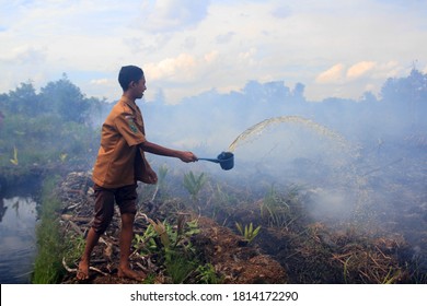 Pekanbaru, Indonesia. 15 December 2016: A Child Still Wearing A School Uniform, Tries To Extinguish A Peatland Fire.