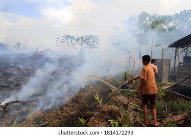 Pekanbaru, Indonesia. 15 December 2016: A Child Still Wearing A School Uniform, Tries To Extinguish A Peatland Fire.