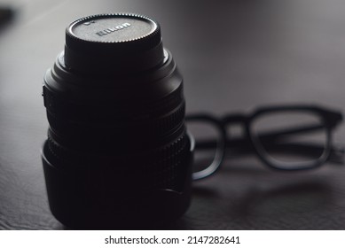 PEKANBARU, INDONESIA - APRIL 17th, 2022 - A Focused Black Lens Nikon With Glasses In The Back