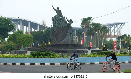 PEKANBARU, Indonesia - AUGUST 30, 2019 : two men cycling next to Tugu Tarian Rakyat or Zapin Dance Monument Pekanbaru, Pekanbaru, Indonesia.