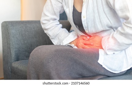 Pelvic pain stomachache medical healthcare concept. Hands of young woman on stomach as pain or ache from menstruation cramp, indigestion, gastrointestinal, diarrheas or female diseases problem