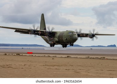 PEMBREY, WALES - APRIL 13 2021: A Royal Air Force Lockheed C-130J 'Super Hercules' performing tactical landings and takeoffs from the public beach at Cefn Sidan Sands in West Wales.