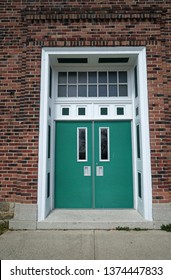 Pen Argyl, Pennsylvania / USA - April 6 2019: Double green doors for a red brick building.  Above the doors is a transom window.  This is Pen Argyl High School.