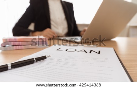 Pen and business loan application form ,money with bank employees approve contract in background. 