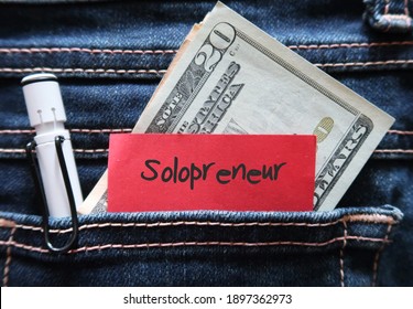 Pen , cash dollars money , red note in jeans pocket written SOLOPRENEUR ,a  person who sets up and runs business on their own