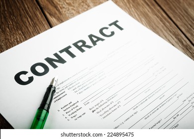 Pen And Contract Papers On Wooden Desk