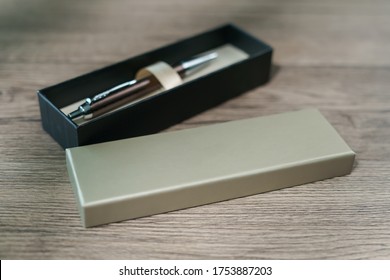 A pen in a gift box on brown wood table background.