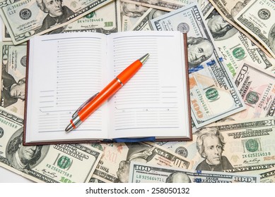 pen lying  on open notebook with dollars background