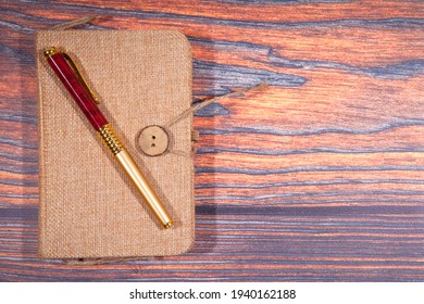Pen and notebook close up on rustic wooden table. Top view