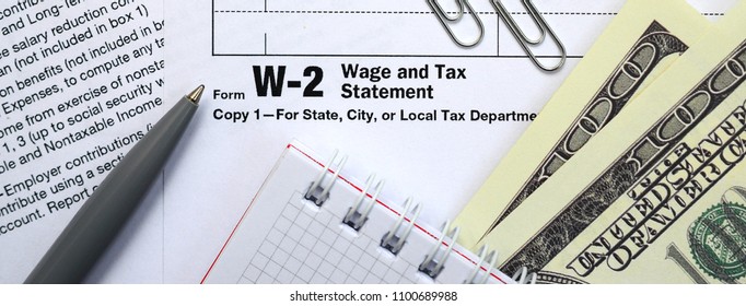 The Pen, Notebook And Dollar Bills Is Lies On The Tax Form W-2 W