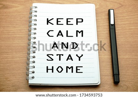 Pen and notebook written keep calm,stay home over wooden background