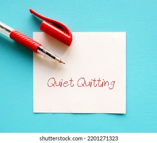 Pen on blue background with handwritten text QUIET QUITTING, workplace buzzword of employees  limited tasks, avoid working long hours, to set clear boundaries to improve work life balance