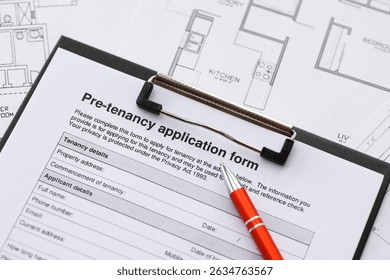 Pen on pre-tenancy application form and planning blueprints of residential building project close up. Pre tenancy application signature concept