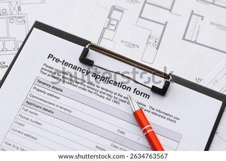 Pen on pre-tenancy application form and planning blueprints of residential building project close up. Pre tenancy application signature concept