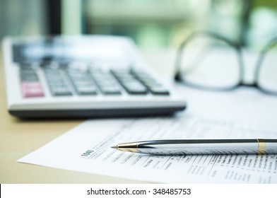 Pen On Tax Form With Blur Calculator And Eyeglasses Background