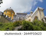 Pena Palace, Sintra: A fairytale castle perched on a dramatic hilltop, the Portuguese crown jewel, a romantic architectural masterpiece, a vibrant mirage against the sky, symbolizing Sintra