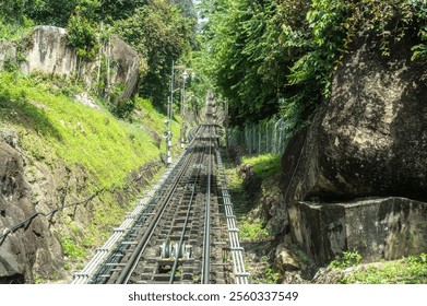 Penang Hill railway tracks leading into tunnel surrounded by lush greenery, steep incline funicular train route, scenic hillside view, popular travel destination, Malaysian heritage site - Powered by Shutterstock