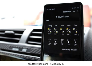 PENANG, MALAYSIA - 15 NOV 2019: User Browsing Google Weather Application On Android Phone Inside The Car. Google Weather Is A Most Popular Weather  Forecast Service Provided By Google Inc.  