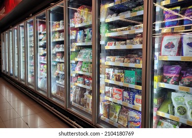 PENANG, MALAYSIA - 2 JAN 2022: Interior view of huge refrigerator shelves with various frozen food and dairy products in a grocery store, Penang. Soft focus image.
