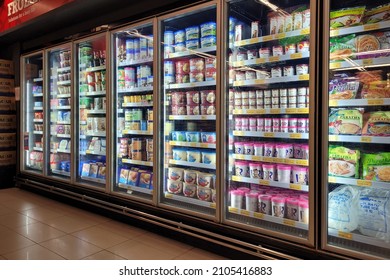 PENANG, MALAYSIA - 2 JAN 2022: Interior view of huge refrigerator shelves with various frozen food and dairy products in a grocery store, Penang. Soft focus image.