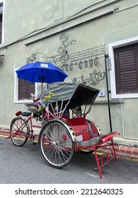 Penang, Malaysia - 5 April 2022: Old Red Trishaw, Three Wheels Vintage Stop Beside Street In George Town, Penang Town Area. Soft Focus