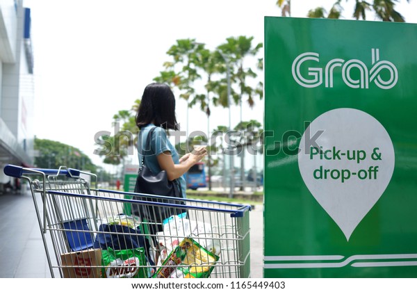PENANG, MALAYSIA - AUGUST 27, 2018 : Passenger is\
waiting for Grab car at pick up location. Grab is a Singapore based\
company that offers ride-hailing and logistics services through its\
app.