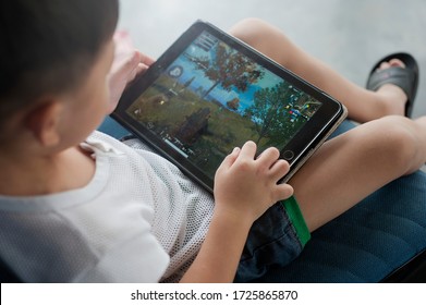 Penang, Malaysia - January 14, 2020 : Little kid's using digital touchscreen phone tablet computer playing games.