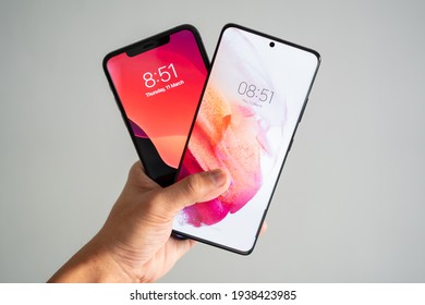 PENANG, MALAYSIA - MAR 11, 2021: Hand Holding Samsung Galaxy S21 Ultra 5G Front View Comparison With Apple IPhone 11 Pro Max In Isolated White Background