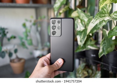 PENANG, MALAYSIA - MAR 11, 2021: Hand Holding The Latest Samsung Galaxy S21 Ultra 5G Phantom Black Color And Showing The Back Of The Phone And Brand New Camera Lens In Green Leaf Background