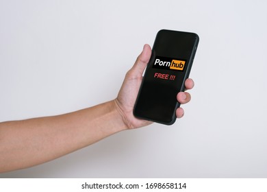 PENANG, MALAYSIA - MAR 16, 2020: Hand holding a mobile phone with alert message “PORNHUB FREE” on the screen with Isolated white background