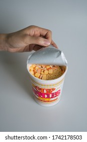 PENANG, MALAYSIA - SEP 01, 2019: Lady’s hand open up the Customate Japan Cup Noodles from Cup Noodles Museum Osaka Ikeda