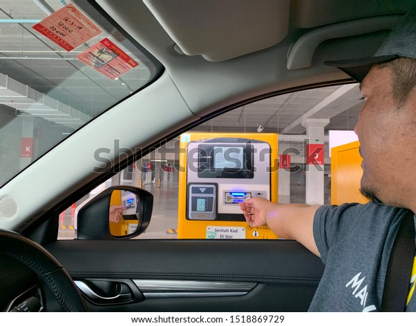 PENANG,MALAYSIA-CIRCA SEPTEMBER,2019:Man\
inserting parking ticket in parking machine for\
checkout.
