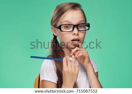 pencil in hand schoolgirl with glasses on green background portrait                               