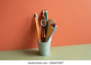Pencil holder on khaki desk. red wall background. workspace, office supply - Shutterstock ID 2206475097
