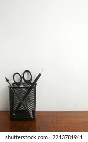 Pencil Holder With Some Stationery On Wooden Desk With Blank White Wall Background. Free Space For Your Text