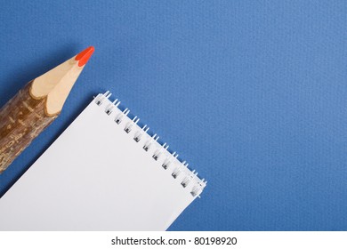 Pencil and a notebed on a blue background.