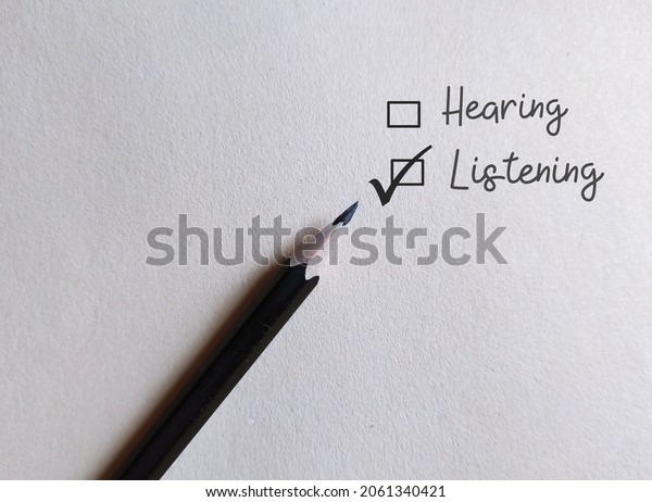 Pencil on white paper with check\
box HEARING and LISTENING, concept of choose to listen than just\
hear, pauy more attention and understand meaning behind the\
words