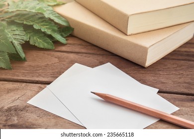 Pencil With Paper And Book On Wooden Table