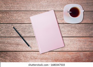 Pencil and a pink covered notebook on wooden table. Bird eye view, mock-up concept.